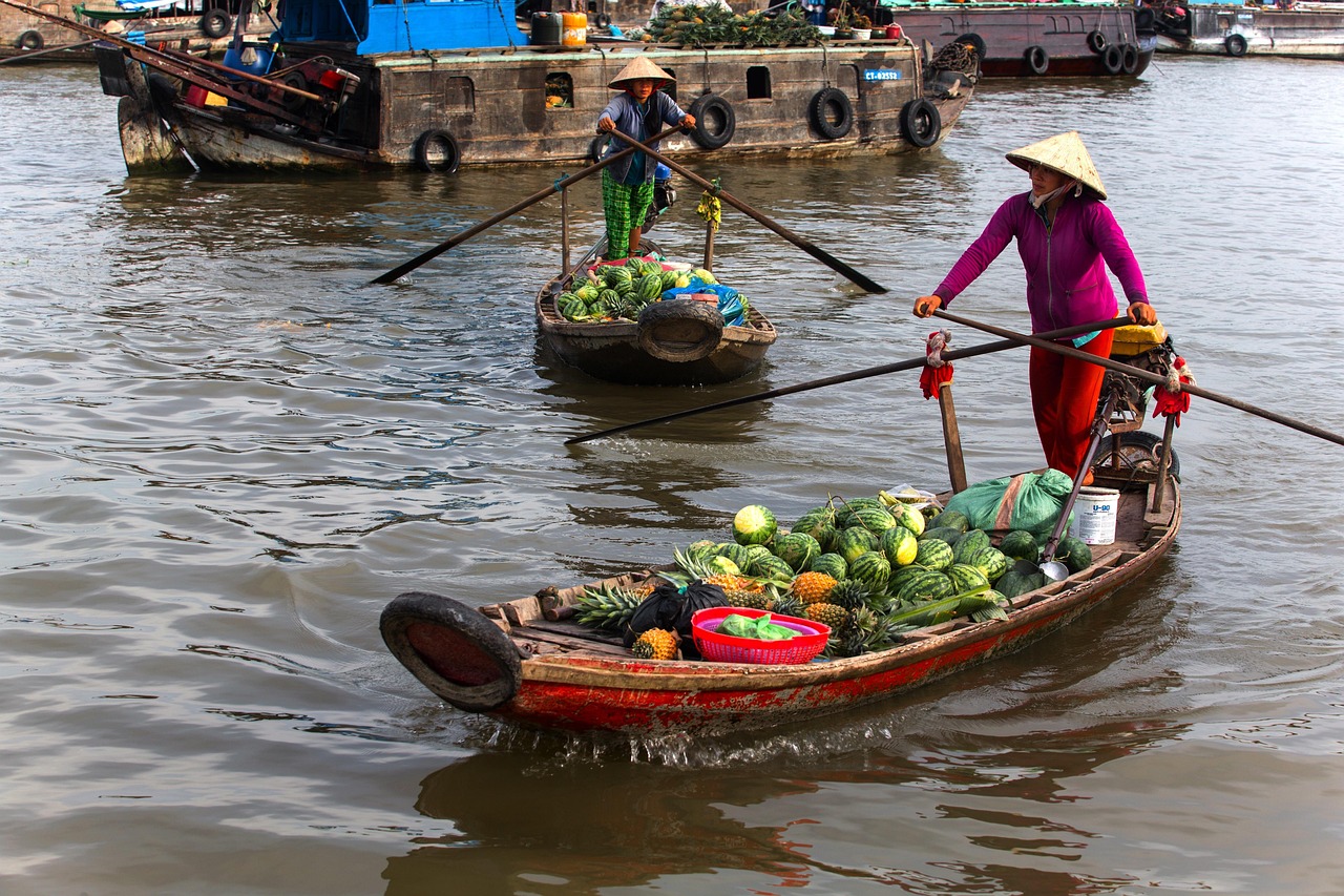 Những chiếc xuồng gỗ chở đầy trái cây và rau củ trên chợ nổi miền Tây, người bán hàng đội nón lá đứng chèo