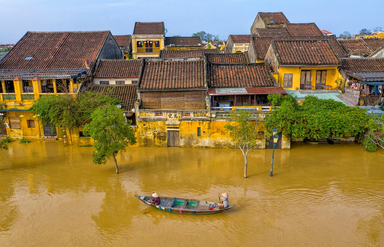 Phố cổ Hội An ngập trong nước lũ sông Thu Bồn, nước đục dâng đến mặt tiền những ngôi nhà vàng và một chiếc thuyền nhỏ phía trước