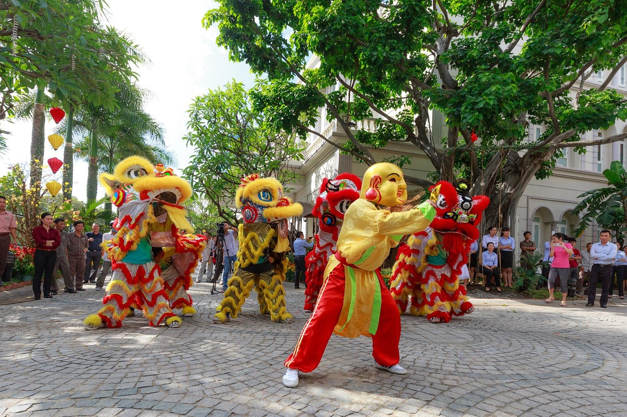 Vietnamese troupe performing the unicorn dance (múa lân) in red and gold costumes on a tree-lined street