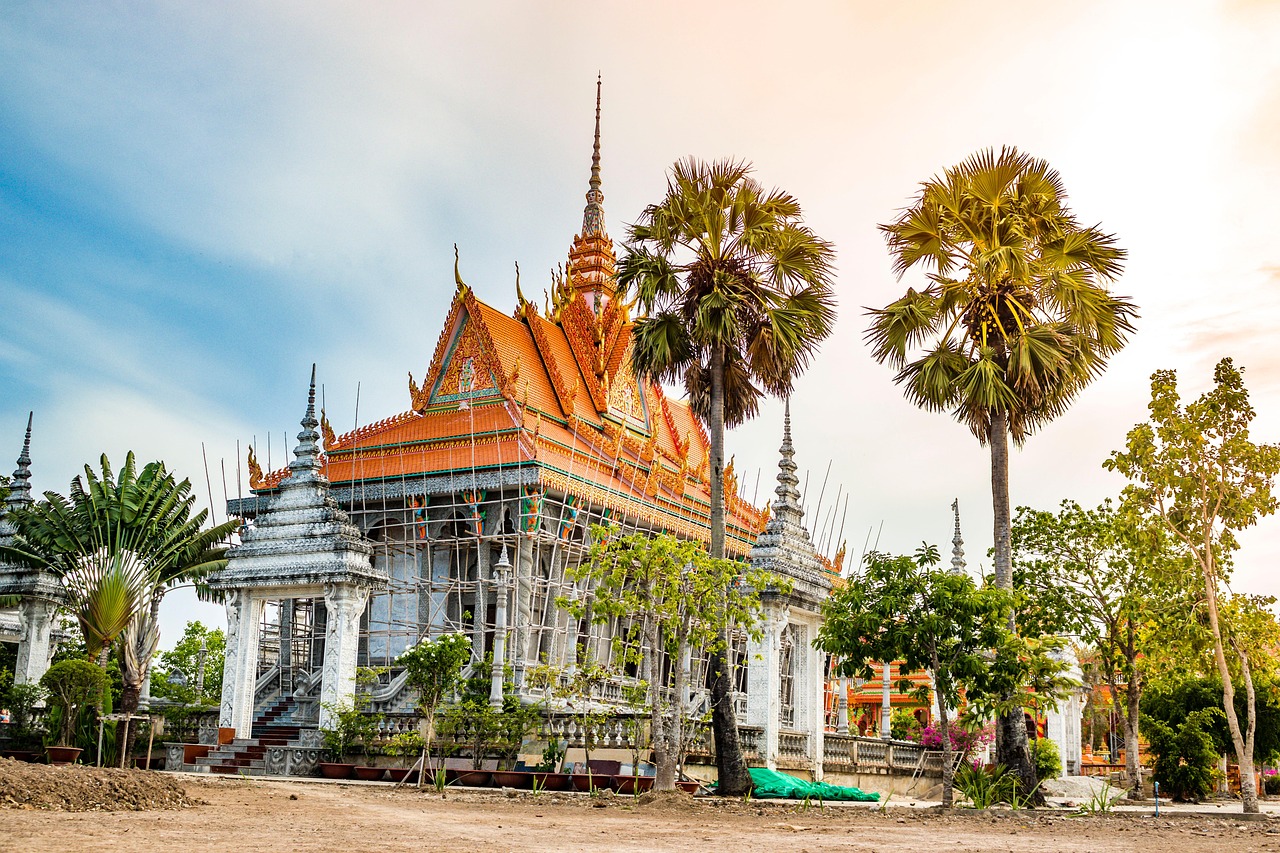 Ngôi chùa Khmer ở đồng bằng sông Cửu Long với mái cam nhiều tầng và ngọn tháp vàng, xung quanh là các tháp trắng và những cây thốt nốt cao