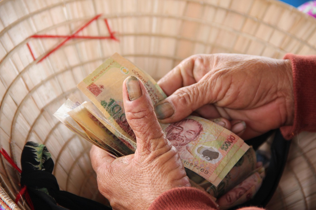 A vendor's hands counting Vietnamese dong banknotes in Hoi An