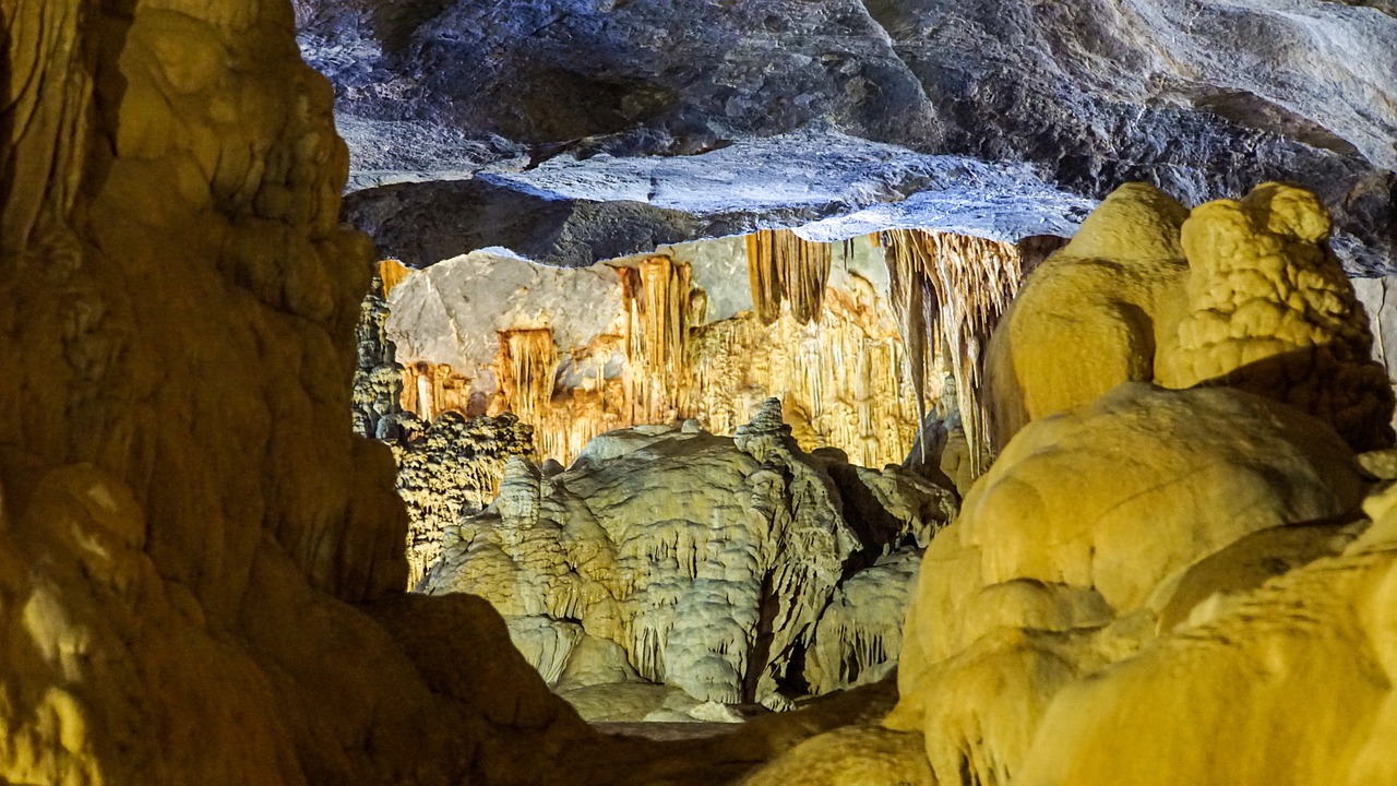 Intérieur d'une grotte du parc de Phong Nha-Kẻ Bàng : stalactites et grosses concrétions dorées éclairées par des projecteurs